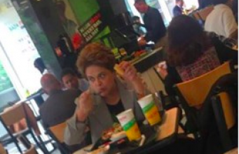 Dilma almoçando sozinha, bandeja de plástico, prato de papel, nos EUA
